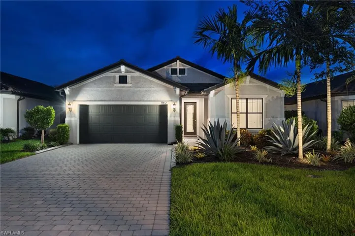 View of front facade with stucco siding, decorative driveway, a lawn, and an attached garage