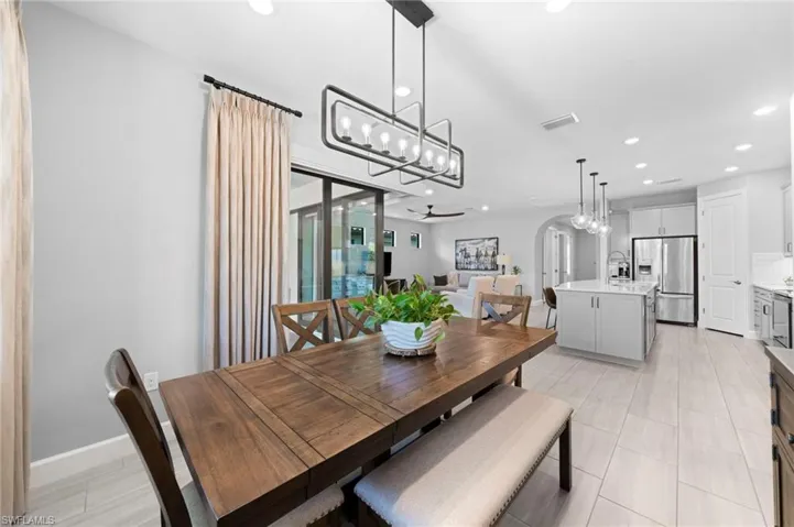 Dining room featuring arched walkways, a chandelier, a ceiling fan, and recessed lighting
