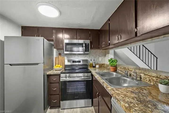 Kitchen featuring wood-finish flooring, dark wood cabinetry, and stone-look countertops