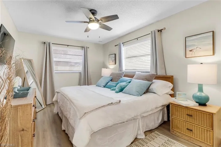 Bedroom with light wood-type flooring, a ceiling fan, and a textured ceiling