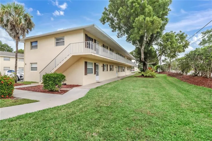 Back of property with a lawn, stucco siding, and a balcony