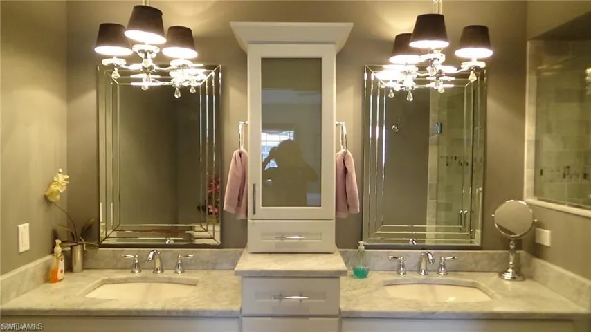 Bathroom featuring a chandelier, double vanity, and a shower with shower door