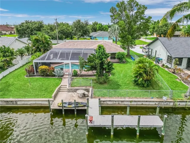 Dock area with a water view, a lawn, and glass enclosure