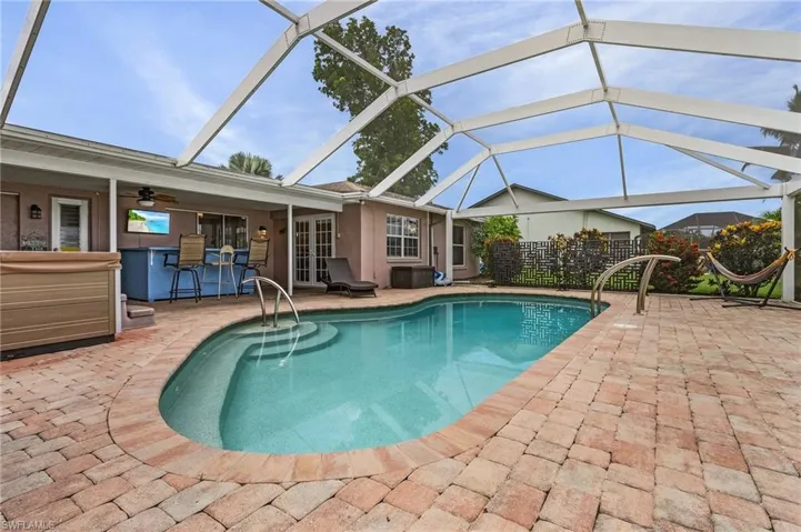 View of swimming pool featuring a hot tub, ceiling fan, a patio area, and glass enclosure