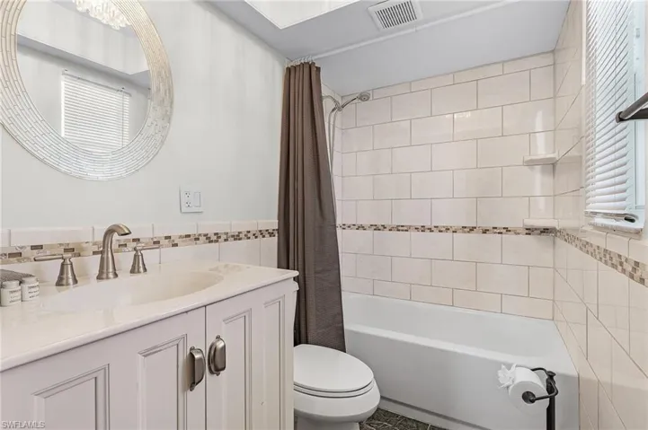 Full bathroom featuring tile walls, vanity, and plenty of natural light