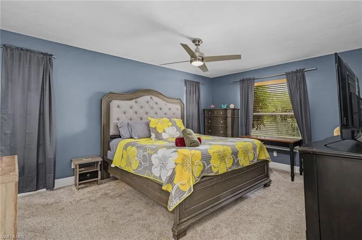 Carpeted bedroom featuring ceiling fan