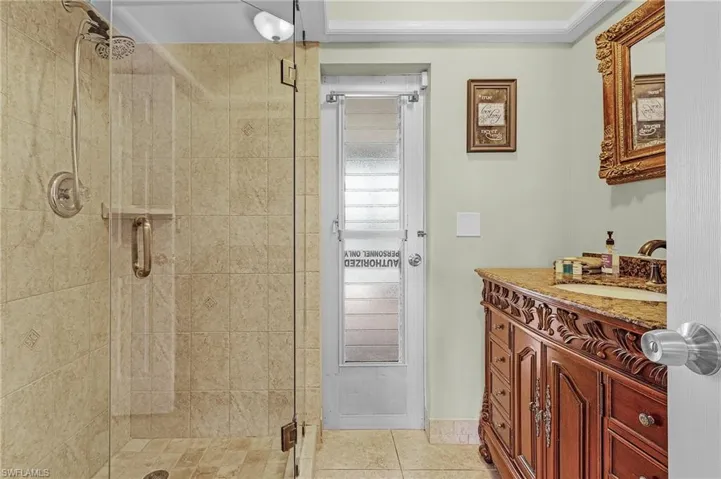 Bathroom featuring vanity, walk in shower, tile patterned flooring, and crown molding