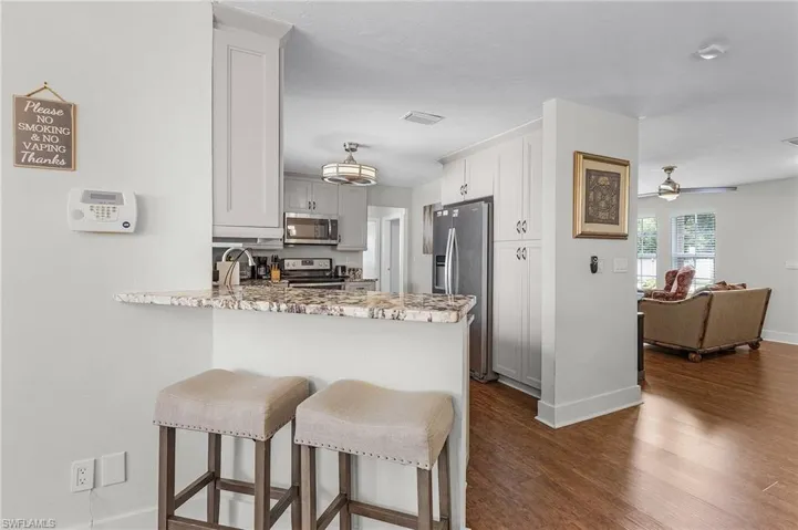 Kitchen featuring appliances with stainless steel finishes, kitchen peninsula, dark hardwood / wood-style floors, white cabinetry, and ceiling fan