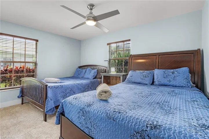 Carpeted bedroom featuring multiple windows and ceiling fan