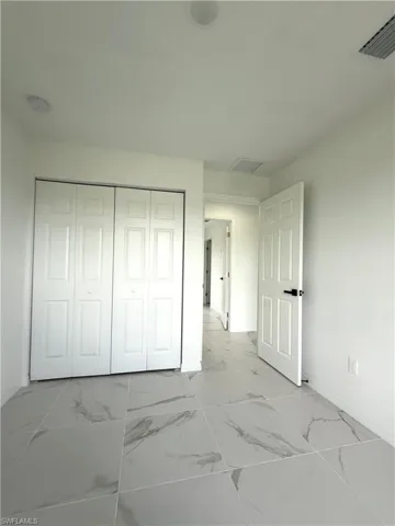 Unfurnished bedroom with marble finish flooring and a closet