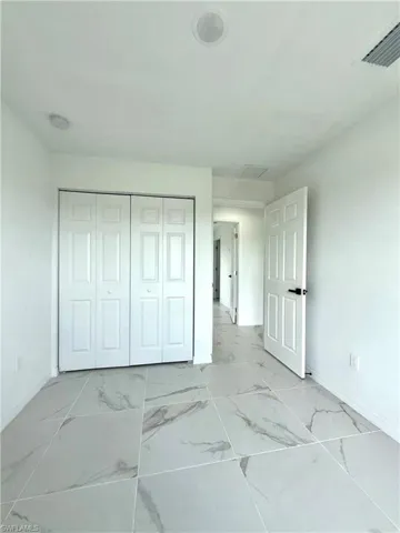 Bedroom featuring light marble finish flooring and a closet