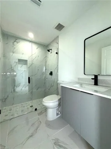 Bathroom with marble look tile flooring, vanity, and a marble finish shower