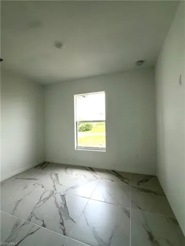 Spare room featuring marble finish floors and baseboards