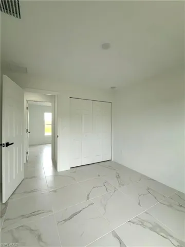 Unfurnished bedroom featuring light marble finish flooring and a closet