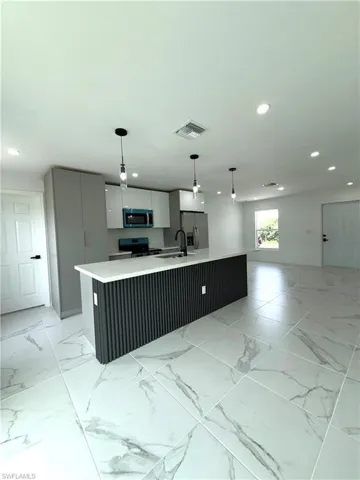 Kitchen with light marble finish flooring, modern cabinets, pendant lighting, stainless steel appliances, and recessed lighting