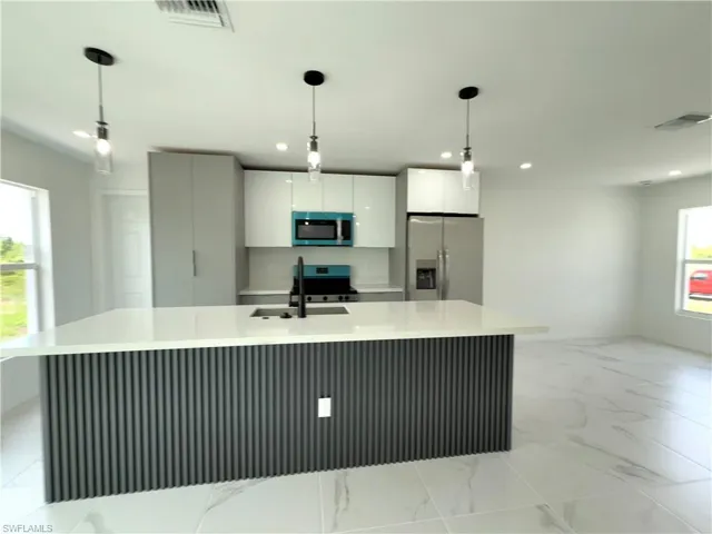 Kitchen with refrigerator with ice dispenser, modern cabinets, pendant lighting, white cabinets, and stainless steel microwave