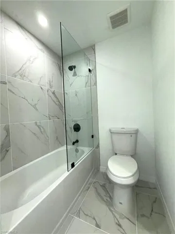 Full bathroom with marble finish flooring, shower / washtub combination, and recessed lighting