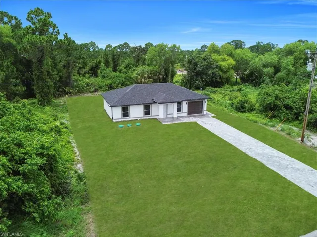 View of front facade featuring a front yard, driveway, and roof with shingles
