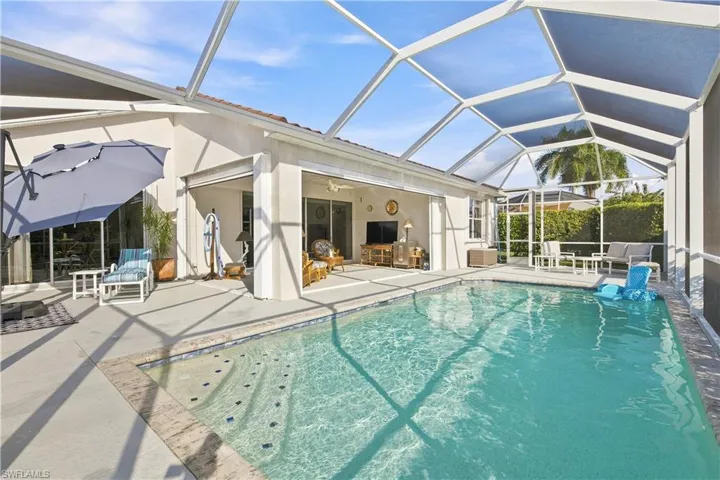 Screened pool enclosure with a rectangular swimming pool, concrete deck, and sliding glass doors