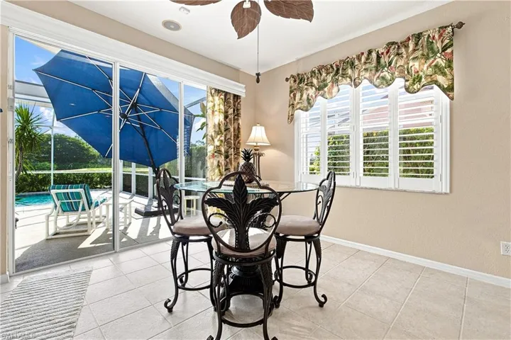 Dinette area with tile flooring, sliding glass doors, plantation shutters, and an outdoor screened-in pool area