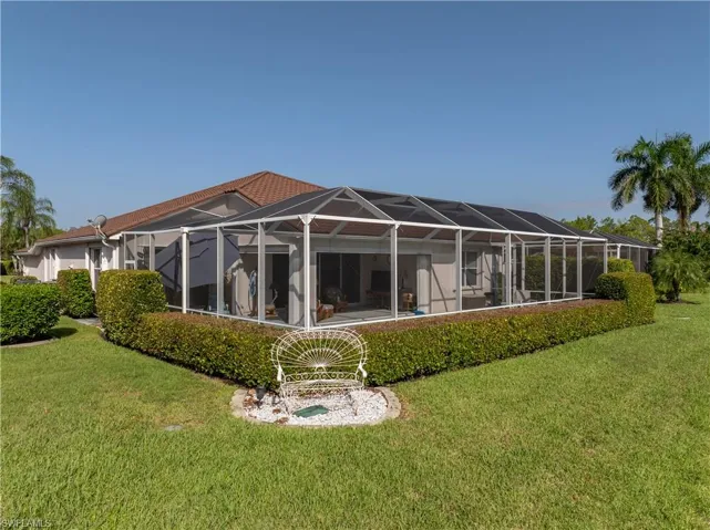 Screened enclosure with a tile roof, stucco exterior, and mature landscaping