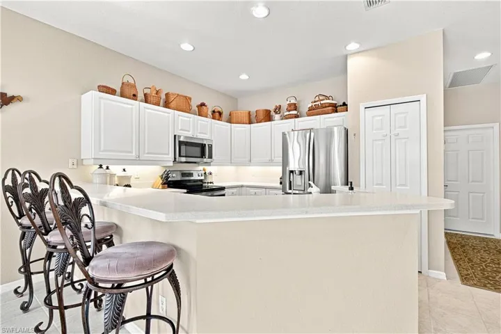 Kitchen featuring white cabinetry, light-toned countertops, recessed lighting, and stainless steel appliances