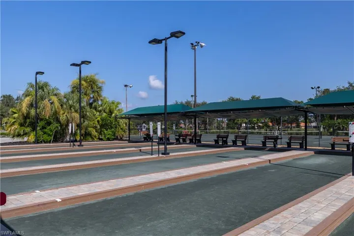 Bocce ball courts featuring shaded seating areas, overhead lighting, and surrounding tropical foliage