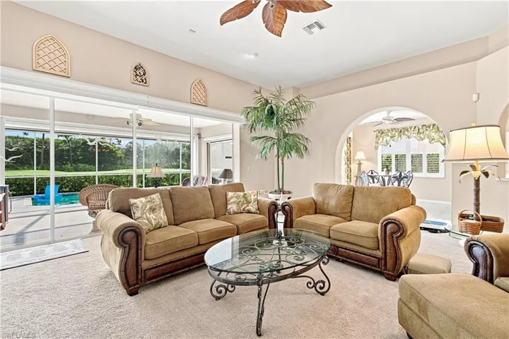 Expansive sliding glass doors, arched entryways, and a ceiling fan with palm-leaf blades