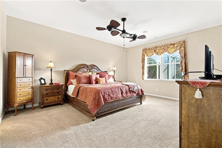 Spacious room featuring neutral wall tones, plush carpet, a window with natural light, and a ceiling fan