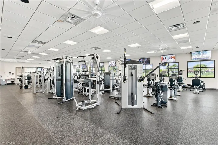 Fitness room featuring rubberized flooring, abundant natural light,  and multiple wall-mounted displays