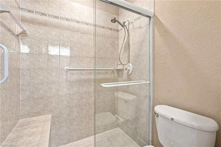 Glass-enclosed shower with tiled walls, integrated shower bench