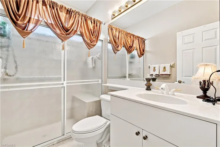 Guest bathroom with white vanity with an integrated sink and shower