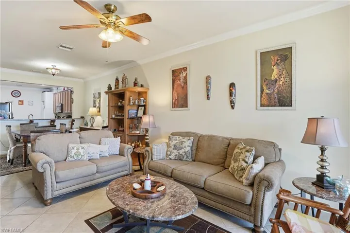 Tiled living room with ornamental molding and a ceiling fan