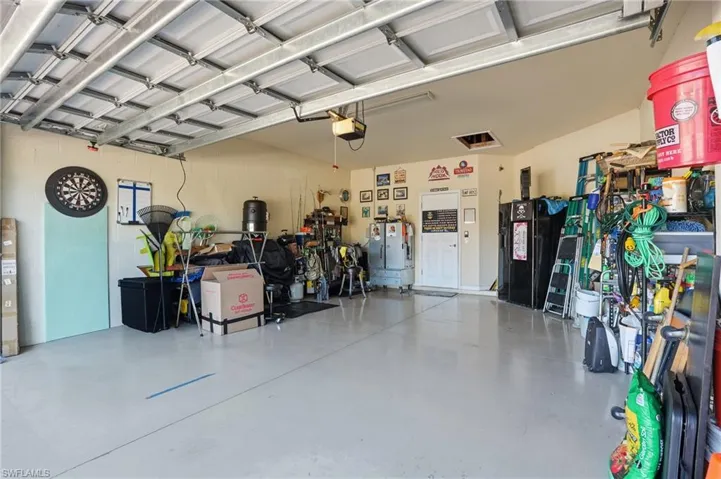 Garage featuring a garage door opener and freestanding refrigerator