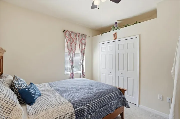 Carpeted bedroom with a closet and a ceiling fan