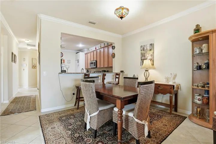 Dining area with crown molding and light tile patterned floors