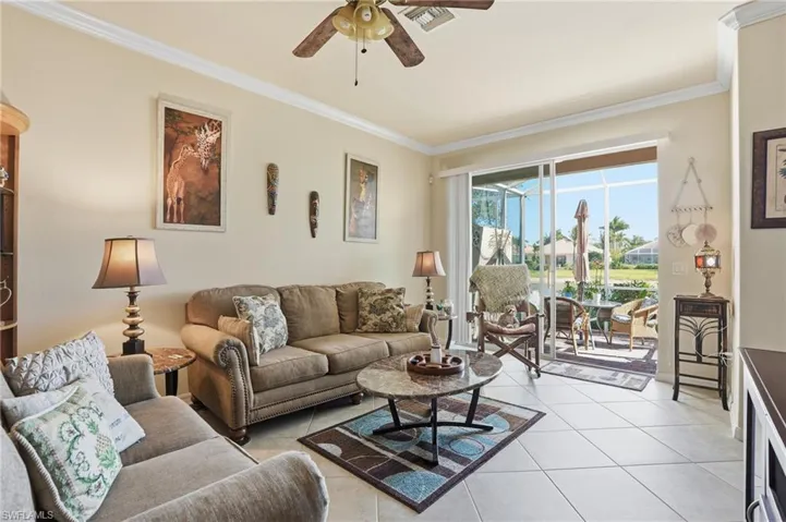 Living room featuring ornamental molding, a ceiling fan, and light tile patterned flooring
