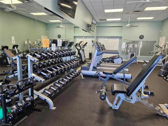 Gym featuring a high drop ceiling and a ceiling fan