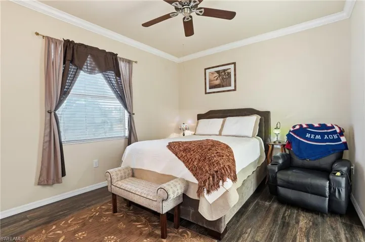 Bedroom featuring crown molding, dark wood-style flooring, and ceiling fan