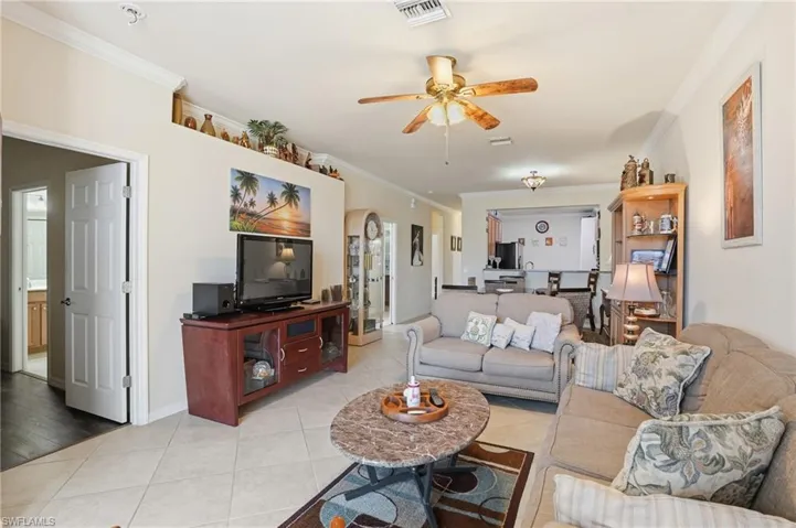 Living room featuring ornamental molding, a ceiling fan, light tile patterned flooring, and arched walkways