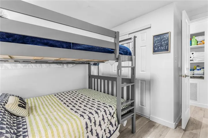 Room featuring a gray bunk bed with integrated ladder, white walls, and wood-finish flooring