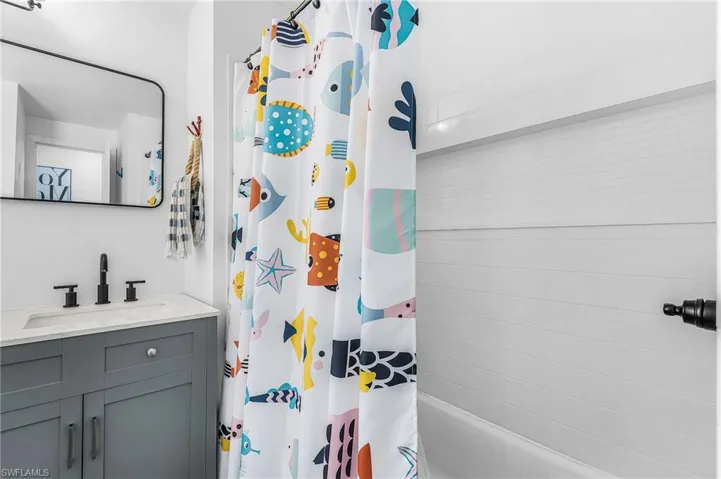 Bathroom featuring a white bathtub with subway tile surround, recessed shelf, and matte black fixture