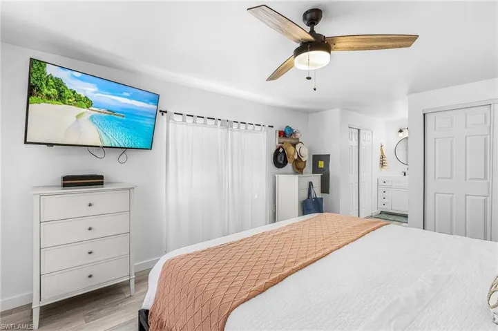 Bright room featuring wood-finish flooring, a ceiling fan with integrated lighting, and a window with white sheer curtains