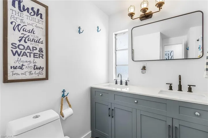 Dual vanity featuring gray shaker-style cabinetry, white countertops, and matte black fixtures