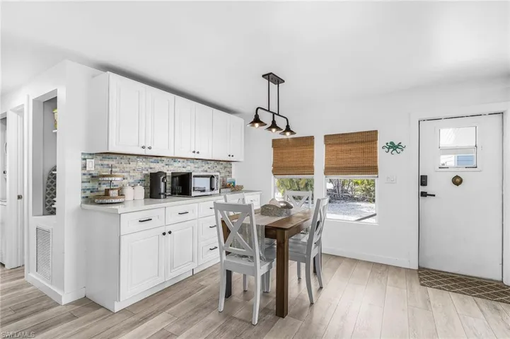 Kitchen and dining area featuring white cabinetry, light countertops, and a blue and beige tile backsplash