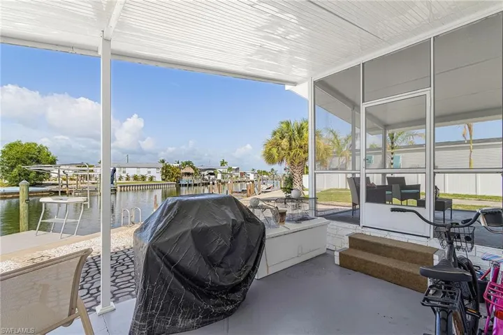 Covered patio with water frontage, a dock, and screened enclosure