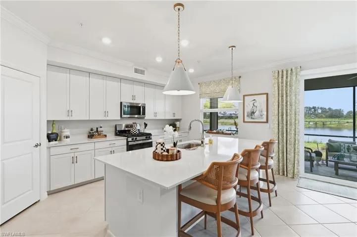 Kitchen with white cabinetry, stainless steel appliances, and a central island with countertop seating