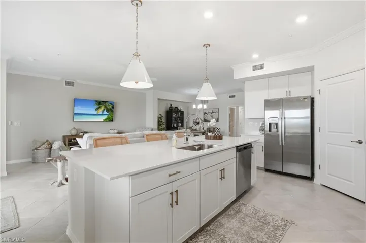 Spacious kitchen island featuring a quartz countertop, integrated sink, and pendant lighting