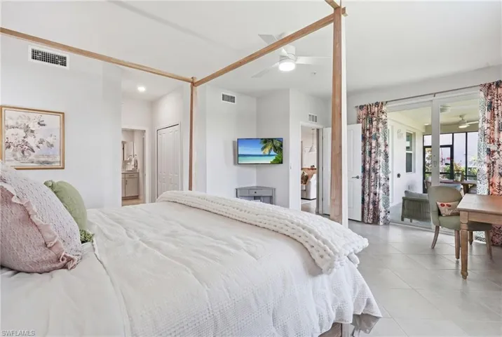 Light-filled bedroom featuring tile flooring, a ceiling fan, and direct access to a private screened balcony through sliding glass doors