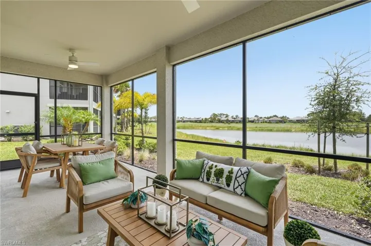 Screened outdoor living area featuring a water body and landscape beyond